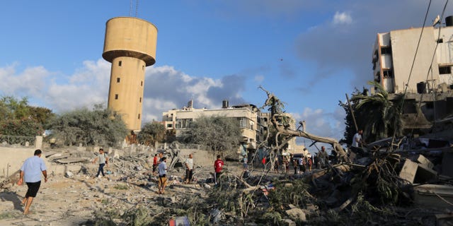 July 25, 2014 - Palestinians walk on the rubble of buildings damaged in an Israeli airstrike in Gaza City,