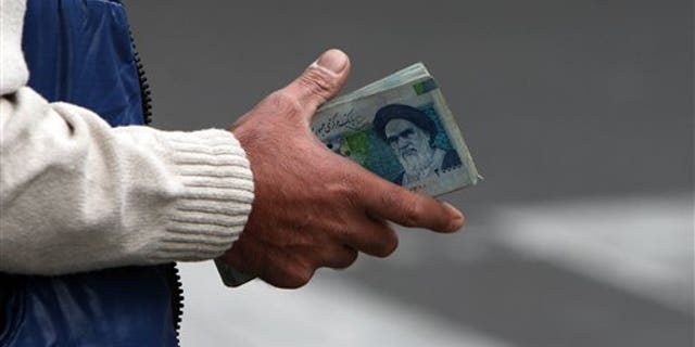Oct. 30, 2008: In this file photo, an Iranian money changer holds currency with Ayatollah Ruhollah Khomeini's image in Tehran, Iran.