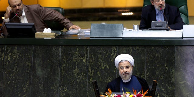Iranian President Hasan Rouhani, bottom, listens during a parliament session to defend the nominees for the three remaining ministries of his cabinet while parliament speaker Ali Larijani speaks, top right, in Tehran, Iran, Sunday, Oct. 27, 2013. Irans parliament has rejected a close ally of Rouhani for a ministerial post. In a vote Sunday, 141 out of 261 lawmakers present voted against Reza Salehi Amiri, who Rouhani nominated as sports and youth minister. (AP Photo)