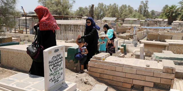 Iraqis visit the grave of a relative on the first day of Eid al-Fitr in Baghdad, Iraq, Monday, July 28, 2014. Monday marked the beginning of the three-day Eid al-Fitr holiday, which caps the Muslim fasting month of Ramadan. Muslims usually start the day by visiting cemeteries, to pay their respects to the dead, and then exchange family visits. (AP Photo/Karim Kadim)