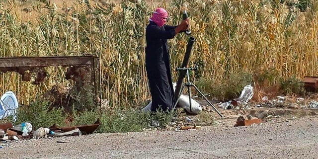 November 22, 2014: An Islamic State group fighter loads a mortar shell during clashes with Iraqi security forces in Ramadi, 70 miles west of Baghdad. (AP)