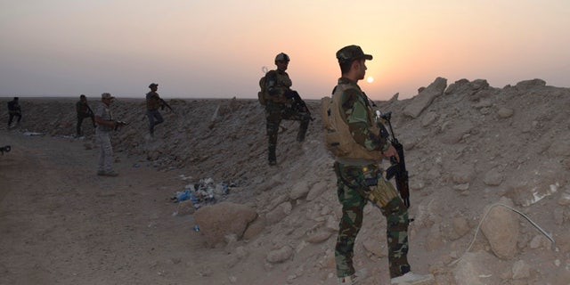 Oct. 15, 2015: Iraqi security forces and Sunni volunteer tribal fighters stand guard as the sun sets after clashes against ISIS.