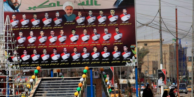 Feb. 24, 2013 - Iraqi women walk past a billboard showing Shiite religious leaders and Shiites who were killed during a fight between US troops and al-Mahdi Army militia in the Jihad neighborhood of west Baghdad, Iraq.