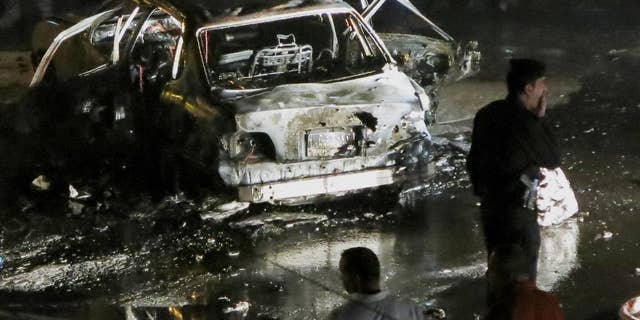 Civilians and security forces gather at the scene of a car bomb explosion in Baghdad's western district of Mansour, Iraq, Monday, April 27, 2015. A series of car bombings targeting busy commercial areas in Iraq's capital left many civilians killed and others wounded, officials said. (AP Photo)