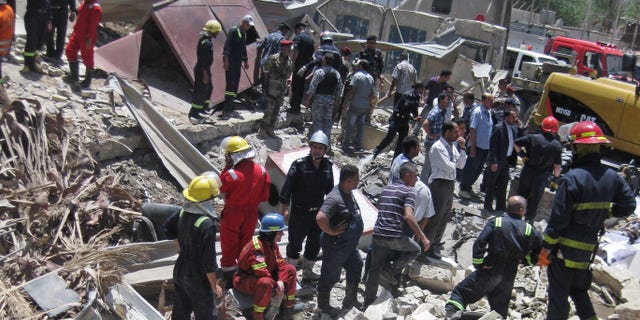 Firefighters and rescuers search for victims at the site of a bomb attack in the central Bab al-Muadham area in Baghdad, Iraq, Monday, June 4, 2012. A suicide bomber detonated explosives in a car outside Iraq's main religious affairs office for Shiite Muslims tearing down part of the three-story building and killed and wounded scores of people, police said. (AP Photo/Hadi Mizban)