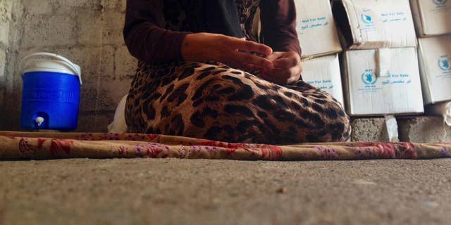 In this photo taken Wednesday, Oct. 8, 2014, a 15-year-old Yazidi girl captured by the Islamic State group and forcibly married to a militant in Syria sits on the floor of a one-room house she now shares with her family after escaping in early August, while speaking in an interview with The Associated Press in Maqluba, a hamlet near the Kurdish city of Dahuk, 260 miles (430 kilometers) northwest of Baghdad, Iraq. The girl was among hundreds of women and girls from the Yazidi religious minority captured by Islamic State fighters in early August when the militants overran their hometown of Sinjar in northwestern Iraq. Hundreds were killed in the attack, and tens of thousands fled for their lives, most to Kurdish-held parts of the north. (AP Photo/Dalton Bennett)