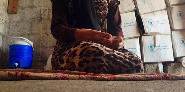 In this photo taken Wednesday, Oct. 8, 2014, a 15-year-old Yazidi girl captured by the Islamic State group and forcibly married to a militant in Syria sits on the floor of a one-room house she now shares with her family after escaping in early August, while speaking in an interview with The Associated Press in Maqluba, a hamlet near the Kurdish city of Dahuk, 260 miles (430 kilometers) northwest of Baghdad, Iraq. The girl was among hundreds of women and girls from the Yazidi religious minority captured by Islamic State fighters in early August when the militants overran their hometown of Sinjar in northwestern Iraq. Hundreds were killed in the attack, and tens of thousands fled for their lives, most to Kurdish-held parts of the north. (AP Photo/Dalton Bennett)