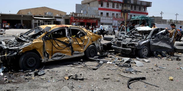June 9, 2014 - Civilians and security forces inspect the site of a suicide attack in Tuz Khormato, 130 miles north of Baghdad, Iraq. A suicide bomber drove his explosive-laden truck into a checkpoint leading up to the offices of the Patriotic Union of Kurdistan and the nearby Kurdistan Communist Party. As people rushed to the site of the explosion, another truck bomb exploded, presumably detonated by remote control.