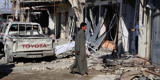 March 23, 2015 - A man inspects the site of a car bomb explosion in a busy commercial street at the Habibiya section of Baghdad's Sadr City, Iraq. Multiple bombings in the Iraqi capital killed and wounded many, Iraqi officials said.
