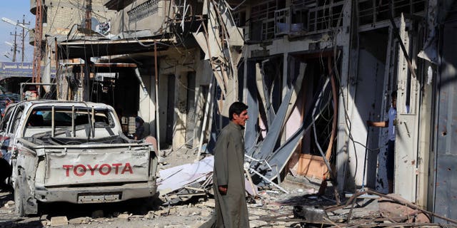 March 23, 2015 - A man inspects the site of a car bomb explosion in a busy commercial street at the Habibiya section of Baghdad's Sadr City, Iraq. Multiple bombings in the Iraqi capital killed and wounded many, Iraqi officials said.