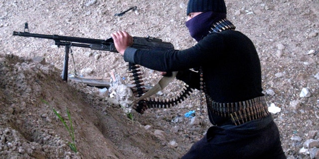 Jan. 19, 2014 - A gunmen takes cover during clashes with Iraqi security forces outside Fallujah, 40 miles west of Baghdad, Iraq.