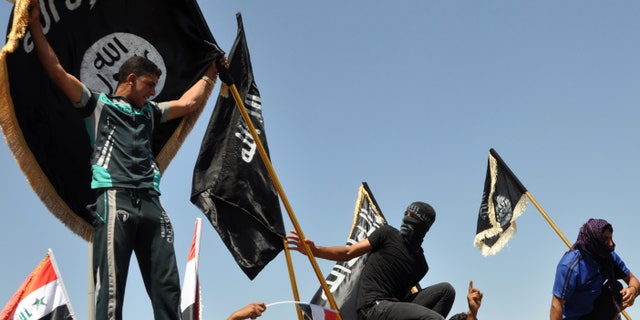 Masked Sunni protesters wave Islamist flags while others chant slogans at an anti-government rally in Fallujah, Iraq, April 26, 2013. The leader of Al Qaeda's Iraq arm, Abu Bakr al-Baghdadi, defiantly rejected an order from the terror network's global command to scrap a merger with the organization's Syria affiliate, according to a message purporting to be from Al-Baghdadi that was posted online June 15, 2013.