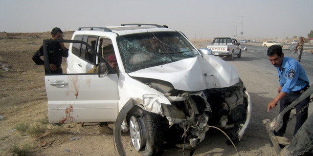 July 22, 2013 - Iraqi policemen prepare to tow away a damaged sport utility vehicle following a drive-by shooting in Kirkuk, north of Baghdad, Iraq.