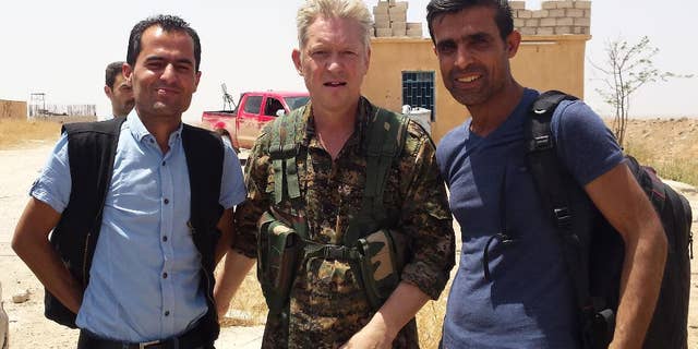 In this handout photo provided by Kurdish journalist Mohammed Hassan, taken on May 19, 2015, Michael Enright, center, a British actor who has had minor roles in Hollywood films, wears the Kurdish fighters military uniform after he joined them battling against the Islamic State group, near Tel Tamr town, northeast Syria. Enright, who played a deckhand in “Pirates of the Caribbean: Dead Man’s Chest,” appears in a video released by the Kurdish People’s Protection Units, known as the YPG. The video shows him in a trench with other fighters firing an assault rifle.