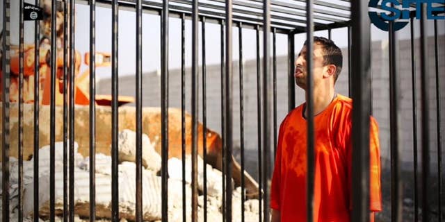 FILE - This still image made from video released by Islamic State group militants and posted on the website of the SITE Intelligence Group in this Tuesday, Feb. 3, 2015 file photo, purportedly shows Jordanian pilot Lt. Muath al-Kaseasbeh standing in a cage just before being burned to death by his captors. The video featured production techniques used in other clips from the militants. But unlike those that showed beheadings in which the hostages or their killer delivered a message before being killed, the pilot video is longer and involves a story-telling narrative and at least four cameras, along with advanced editing techniques. The death of the 26-year-old pilot, who fell into the hands of the militants in December when his Jordanian F-16 crashed near Raqqa, Syria, followed a weeklong drama over a possible prisoner exchange. (AP Photo/SITE Intelligence Group, File)