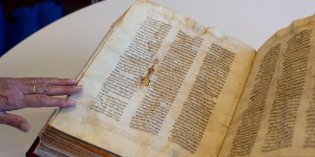 FILE - In this Oct. 5, 2014 file photo, a library official shows a Jewish manuscript smuggled into Israel from Damascus in a Mossad spy operation in the early 1990s, in Jerusalem. The manuscript is one of the earliest existing complete manuscripts of the Hebrew bible. Two decades after Israeli spies helped whisk eight ancient Hebrew bibles from Damascus to Jerusalem, Israel’s national library asked an Israeli court Monday, Dec. 8, 2014 to grant it official custodianship over the manuscripts, a move that is liable to spark a bitter ownership battle over the some of the Syrian Jewish community’s most important treasures. (AP Photo/Sebastian Scheiner, File)