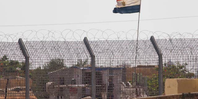 An Egyptian military officer watches at a post in Egypt's northern Sinai Peninsula, as seen from the Israel-Egypt border, in Kerem Shalom village, southern Israel, Wednesday, July 1, 2015. Islamic militants on Wednesday unleashed a wave of simultaneous attacks, including suicide car bombings, on Egyptian army checkpoints in the restive northern Sinai Peninsula, killing tens of soldiers, security and military officials said. (AP Photo/Ariel Schalit)