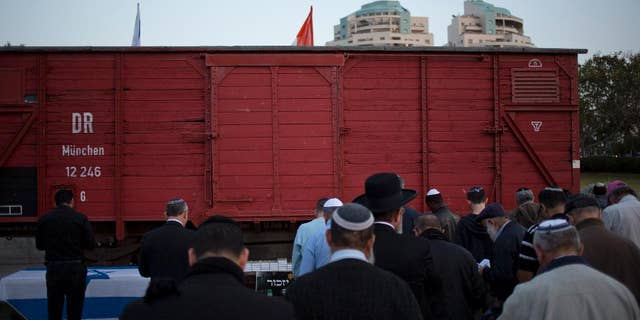 FILE -- People pray next to a wagon from WWII on display on the eve of Holocaust Remembrance Day in Netanya, Israel.