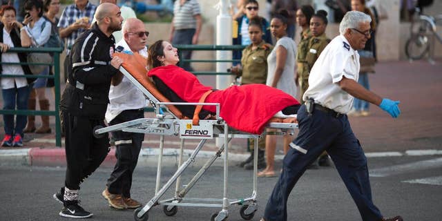 FILE - In this Monday, Nov. 2, 2015 file photo, Israeli rescue personal evacuate a woman after a stabbing attack in Rishon Lezion, Israel. After years of relative quiet in major Israeli cities, a seven-week burst of violence has brought the Palestinian issue back to the country’s heartland and pushed the long-festering issue onto the national agenda. (AP Photo/Ariel Schalit, File)
