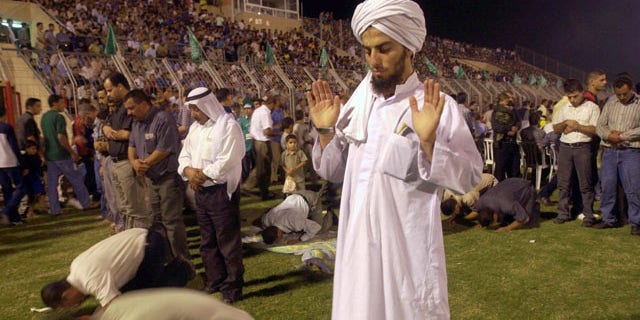 FILE - In this Friday, Sept. 14, 2001 file photo, an Israeli Arab prays alongside other Muslims during a rally of the Islamic movement in the Arab Israeli town of Um El-Fahem. (AP Photo/Elizabeth Dalziel, File)