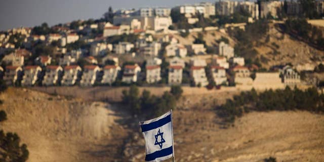 FILE - In this Monday, Sept. 7, 2009 file photo, an Israeli flag is seen in front of the West Bank Jewish settlement of Maaleh Adumim on the outskirts of Jerusalem. The population of Jewish settlers in the occupied West Bank has surged during Prime Minister Benjamin Netanyahu's years in office, growing at more than twice the pace of the overall population, according to official figures obtained in December, 2014. (AP Photo/Bernat Armangue, File)