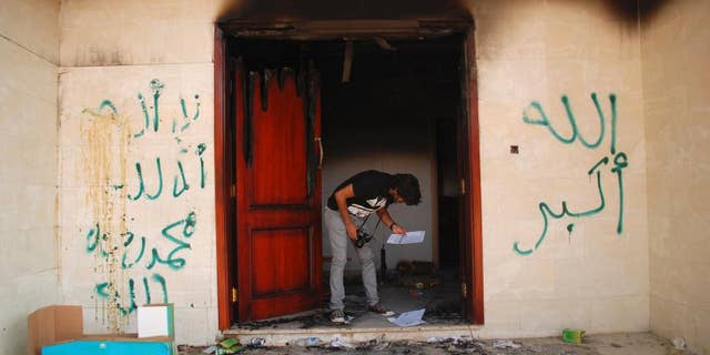 FILE - In this file photo taken Wednesday, Sept. 12, 2012, a man looks at documents at the U.S. Consulate in Benghazi, Libya, the day after an attack that killed four Americans, including Ambassador Chris Stevens. A strange silence has met the U.S. capture of a Libyan militant accused in the 2012 attack that killed the American ambassador and three others. In his hometown of Benghazi in eastern Libya, there have been few threats of revenge, only speculation among supporters and opponents that Ahmed Abu Khattala was betrayed by an insider. (AP Photo/Ibrahim Alaguri, File)