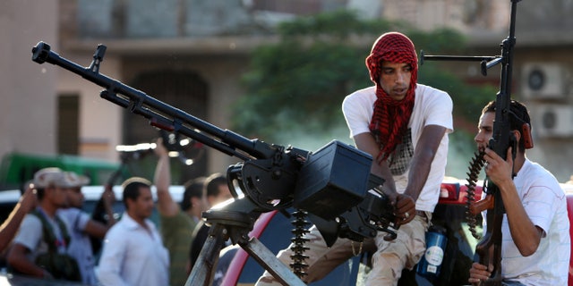 Revolutionary fighters sit on a truck mounted with a machine gun in the Abu Salim neighborhood of Tripoli, Libya, Friday, Oct. 14, 2011.