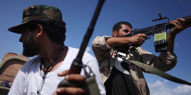 Oct. 18, 201: Revolutionary fighters fire at Qaddafi loyalists in downtown Sirte, Libya.