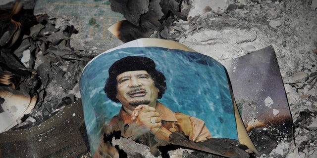 A picture of Libya's ousted leader Muammar Qaddafi is seen in the ashes in downtown Sirte, Libya, Wednesday, Oct. 12, 2011.
