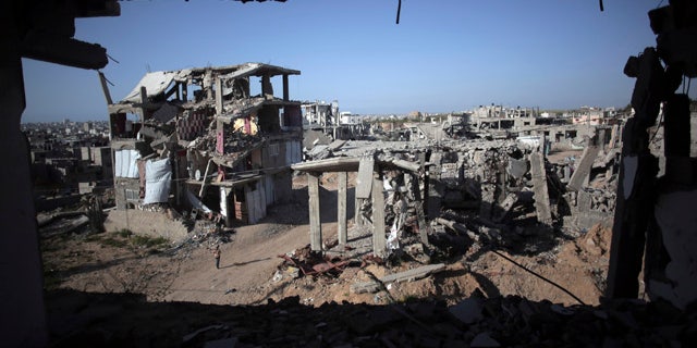 File - In this March 30, 2015 file photo, a Palestinian girl walks next to destroyed houses, in the Shijaiyah neighborhood of Gaza City. (AP Photo/Khalil Hamra, File)