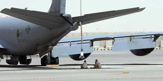 FILE -- In this photo taken Monday, March 9, 2015, U.S. technicians sit under the KC-135 refueling aircraft at the al-Udeid Air Base in Doha, Qatar.