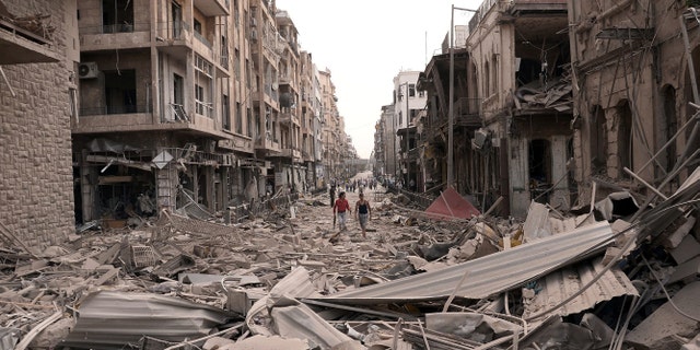 Syrian men walk between buildings destroyed by bombs in Aleppo, Syria, on Oct. 3, 2012.