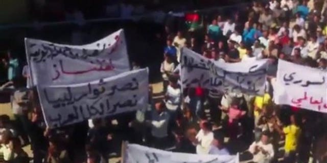 In this image made from amateur video released by Ugarit News and accessed via The Associated Press Television News, a banner at left, in Arabic, reads, "the victory of the Libyan rebels is a victory for all Arabs" in Idlib, Syria.