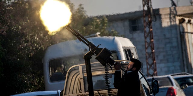Dec. 15, 2012: In this photo, A Free Syrian Army fighter fires a weapon during heavy clashes with government forces at a academy besieged by rebels north of Aleppo, Syria.