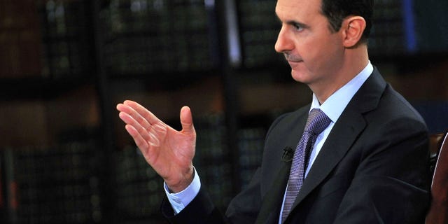 Sept. 29, 2013: In this photo, which AP obtained from Syrian official news agency SANA, has been authenticated based on its contents and other AP reporting, President Bashar Assad gestures as he speaks during an interview with Italy's RAI News 24 TV, at the presidential palace in Damascus, Syria.