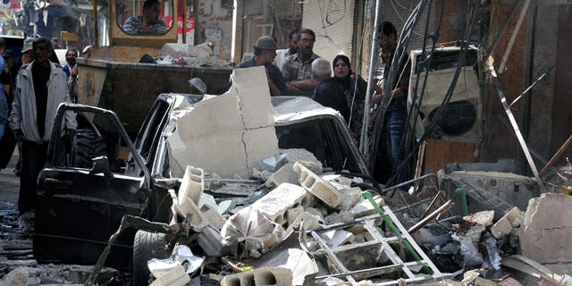 In this photo released by the Syrian official news agency SANA, Syrian citizens gather at the scene of a car bomb exploded in in Damascus, Tuesday September 24, 2013.