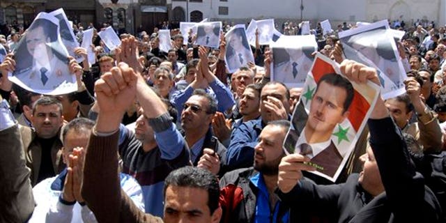 April 15: Syrian pro-government protesters carry pictures of Syrian President Bashar Assad as they shout slogans after Friday prayers outside the Omayyad Mosque in Damascus, Syria. (AP)