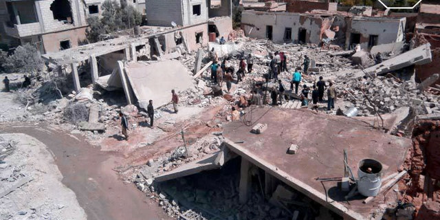 May 21, 2013 - FILE citizen journalism image provided by Qusair Lens, shows Syrian citizens gathering over houses that were destroyed by a Syrian forces air strike in the town of Qusair, near the Lebanon border.