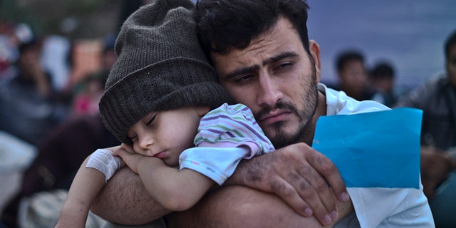 FILE - In this Sunday, Oct. 4, 2015 file photo, a Syrian refugee child sleeps in his father's arms while waiting at a resting point to board a bus, after arriving on a dinghy from the Turkish coast to the northeastern Greek island of Lesbos. Bold ideas for helping Syrian refugees and their overburdened Middle Eastern host countries are gaining traction among international donors who were shocked into action by this year's migration of hundreds of thousands of desperate Syrians to Europe. (AP Photo/Muhammed Muheisen, File)