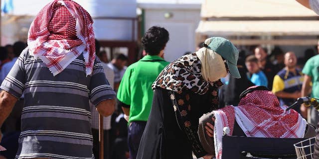 In this Thursday, Oct. 1, 2015 photo, Syrian refugees wait to sign up for a return bus to the Syrian border, at the U.N.-run Zaatari refugee camp near Mafraq, northern Jordan. Growing numbers of Syrian refugees are returning to their war-ravaged homeland from Jordan because they can't survive in exile after drastic aid cuts, can't afford to pay smugglers to sneak them into Europe or are simply homesick. (AP Photo/Raad Adayleh)