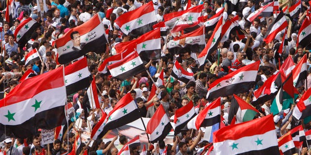 Syrian regime supporters wave their national flags during a demonstration to show their support for President Bashar Assad and to thanks Russia and China for blocking a U.N. Security Council resolution condemning Syria for its brutal crackdown, in Damascus, Syria, on Wednesday Oct. 12, 2011.