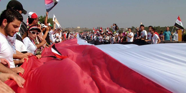 July 10: Thousands of supporters of Syrian President Bashar Assad, carry a gigantic 17,500 yards (16,000 meters) Syrian flag during a pro-Assad demostration, in the Mediterranean city of Latakia, northewest of Damascus, Syria.