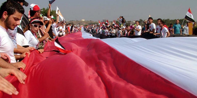 July 10: Thousands of supporters of Syrian President Bashar Assad, carry a gigantic 17,500 yards (16,000 meters) Syrian flag during a pro-Assad demostration, in the Mediterranean city of Latakia, northewest of Damascus, Syria.