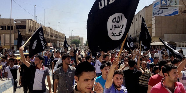 In this June 16, 2014 file photo, demonstrators chant pro-Islamic State group slogans as they carry the group's flags in front of the provincial government headquarters in Mosul, Baghdad.