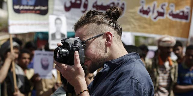 In this Tuesday, April 16, 2013 photo, Luke Somers, 33, an American photojournalist who was kidnapped over a year ago by al-Qaida, uses a camera during a demonstration demanding the release of Yemeni detainees in Guantanamo Bay prison in front of the U.S. embassy in Sanaa, Yemen. Somers and a South African teacher held by al-Qaida militants in Yemen were killed Saturday, Dec. 6, 2014 during a U.S.-led rescue attempt, a raid President Barack Obama said he ordered over an "imminent danger" to the reporter. (AP Photo/Hani Mohammed)