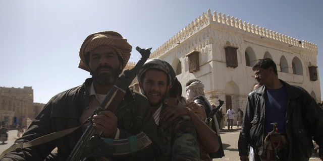 Jan. 25, 2012: Backdropped by Ameriyah religious school which was seized by Al Qaeda militants, a Yemeni armed tribesman, left, holds his rifle as he rides a motorcycle with others in Radda town, 100 miles south of the capital Sanaa, Yemen.