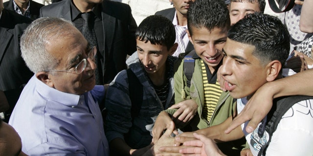 Palestinian Prime Minister Salam Fayyad is surrounded by media and supporters as he visits a school in the West Bank village of Dahiat Al-Barid on the outskirts of Jerusalem, Tuesday, Nov. 2, 2010.