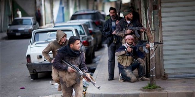 In this Sunday, March 11, 2012 photo, Syrian rebels take position during clashes with government forces in Idlib, north Syria. (AP Photo/Rodrigo Abd)