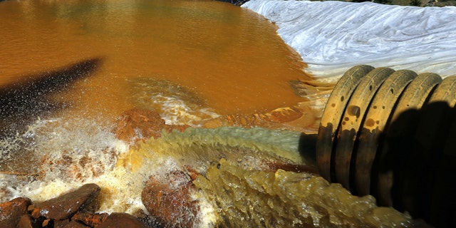 FILE - In this Aug. 14, 2015 file photo, water flows through a series of sediment retention ponds built to reduce heavy metal and chemical contaminants from the Gold King Mine wastewater accident, in the spillway about 1/4 mile downstream from the mine, outside Silverton, Colo. (AP Photo/Brennan Linsley, file)