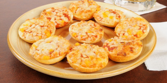 A plate of bagels with pizza toppings and a mug of beer on a bar counter